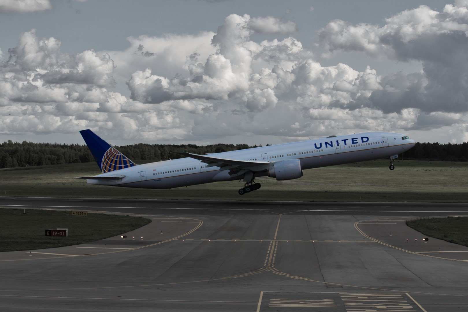 A photo of a huge plane taking off at an airport at a 90 degree angle to the photographer